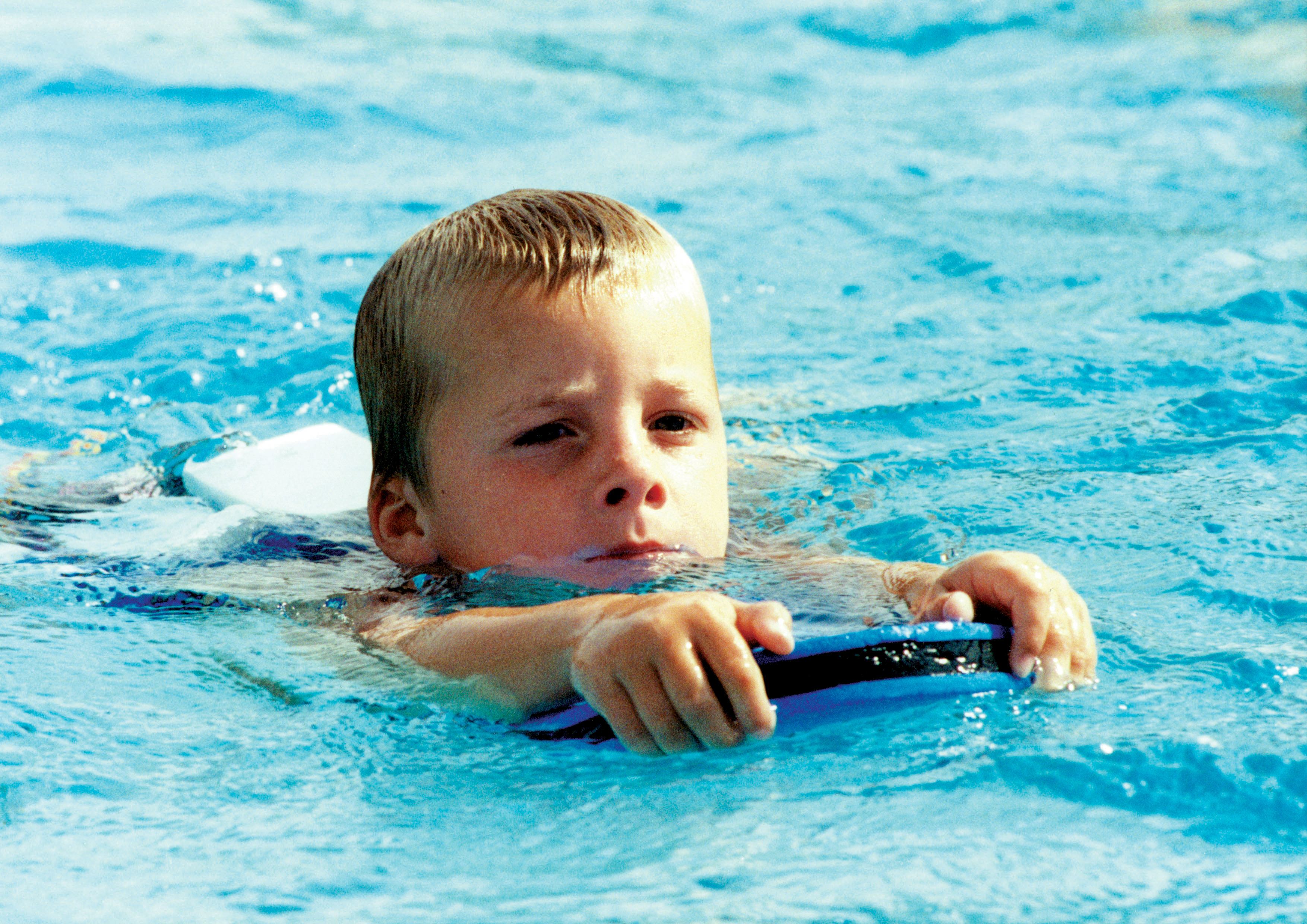 Kind mit Schwimmbrett im Wasser